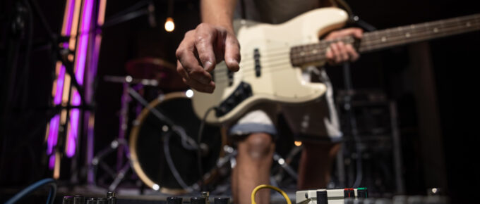 Persona afina una guitarra eléctrica y realiza pruebas de sonido, como parte de la logística de un evento musical.