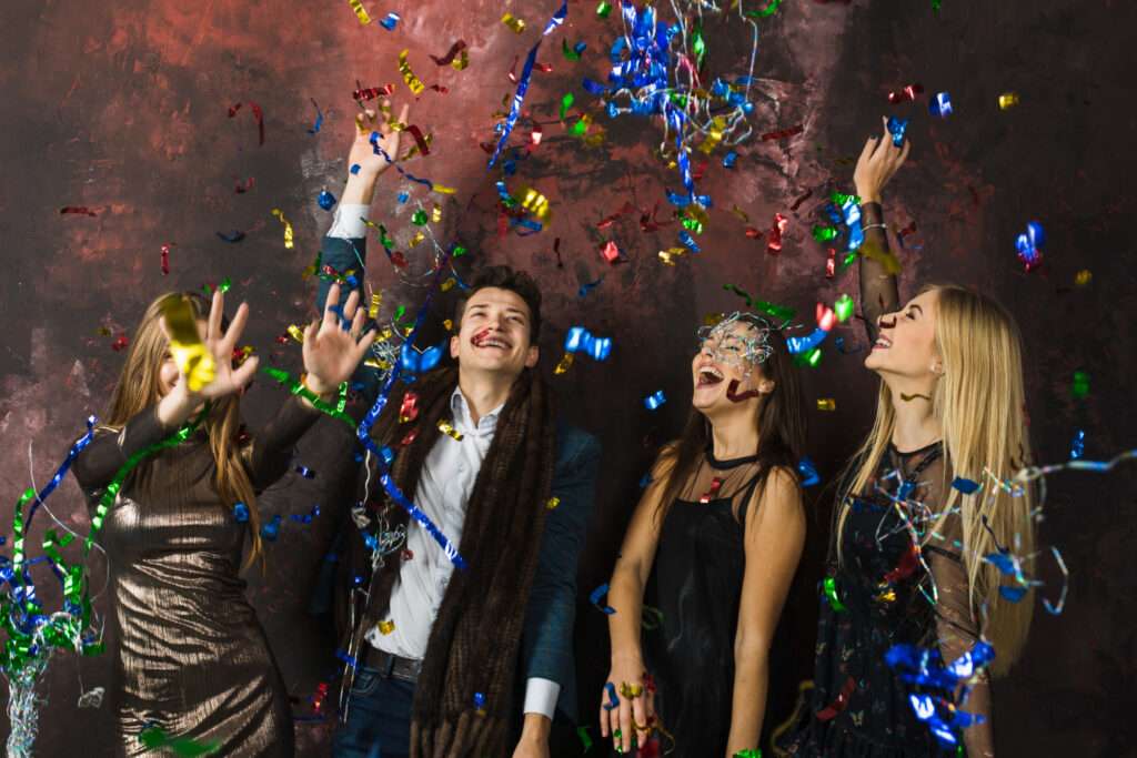  Grupo de cuatro jóvenes disfrutan de una fiesta empresarial, con luces y música. 