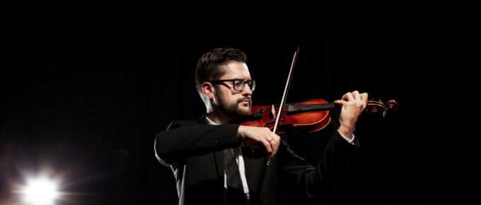 Violinista con su instrumento en mano se presenta en un escenario, para ilustrar el manejo de artistas para eventos culturales.